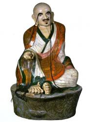  Архат Канакаватса. Китай, 19 в. Папье-маше, роспись. 
 Аюшман Канакаватса - архат, относящийся к 16 старейшим ученикам Будды Шакьямуни. Он наставлял в учении нагов, которые преподнесли ему низку жемчуга или нить драгоценных камней. Архат Канакаватса представлен в лалита-асане, левая рука скрыта в полах одежды, правая рука лежит на колене. Признак - длинные, свисающие до земли брови. 